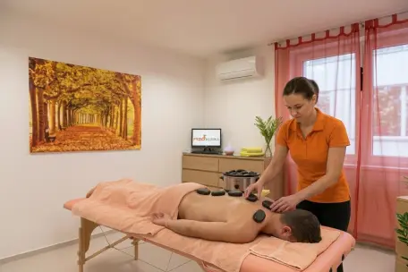 Muž při relaxační masáži zad v podzimně laděném interiéru.